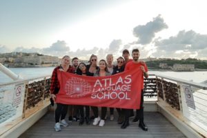 Group of mini stay students and staff with the red Atlas flag in Malta