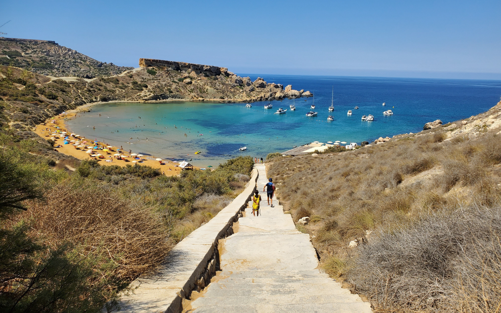 Tourists going downstairs to the natural beach of Għajn Tuffieħa in Malta