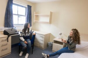 Two girls chatting in the room in Atlas Junior Chichester residential accommodation on campus.