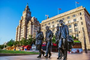 A view of Liverpool featuring iconic buildings and a Beatles tribute, highlighting the city's rich cultural heritage and musical legacy.