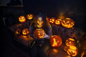 A student holding pumpkins in a festive Halloween setting.