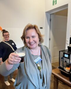 Smiling attendee raises a freshly made Irish coffee during the Erasmus+ cultural session in Wroclaw, celebrating Irish traditions with Atlas Language School.