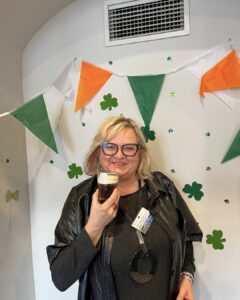 Participant poses with her Irish coffee in front of Irish-themed decorations during the Erasmus+ event in Wroclaw hosted by Atlas Language School.