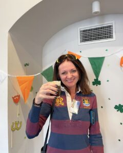 Attendee smiles with her Irish coffee in hand, surrounded by festive green, white, and orange bunting at the Erasmus+ event in Wroclaw.