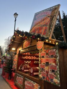 Wooden stall at a Christmas market decorated with lights, selling holiday goods.